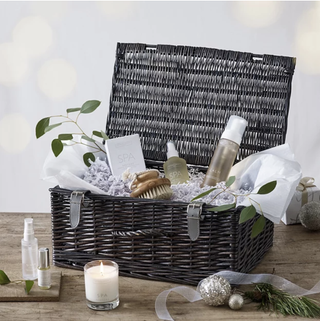 Christmas hamper with a grey basket and wellness treats such as candles