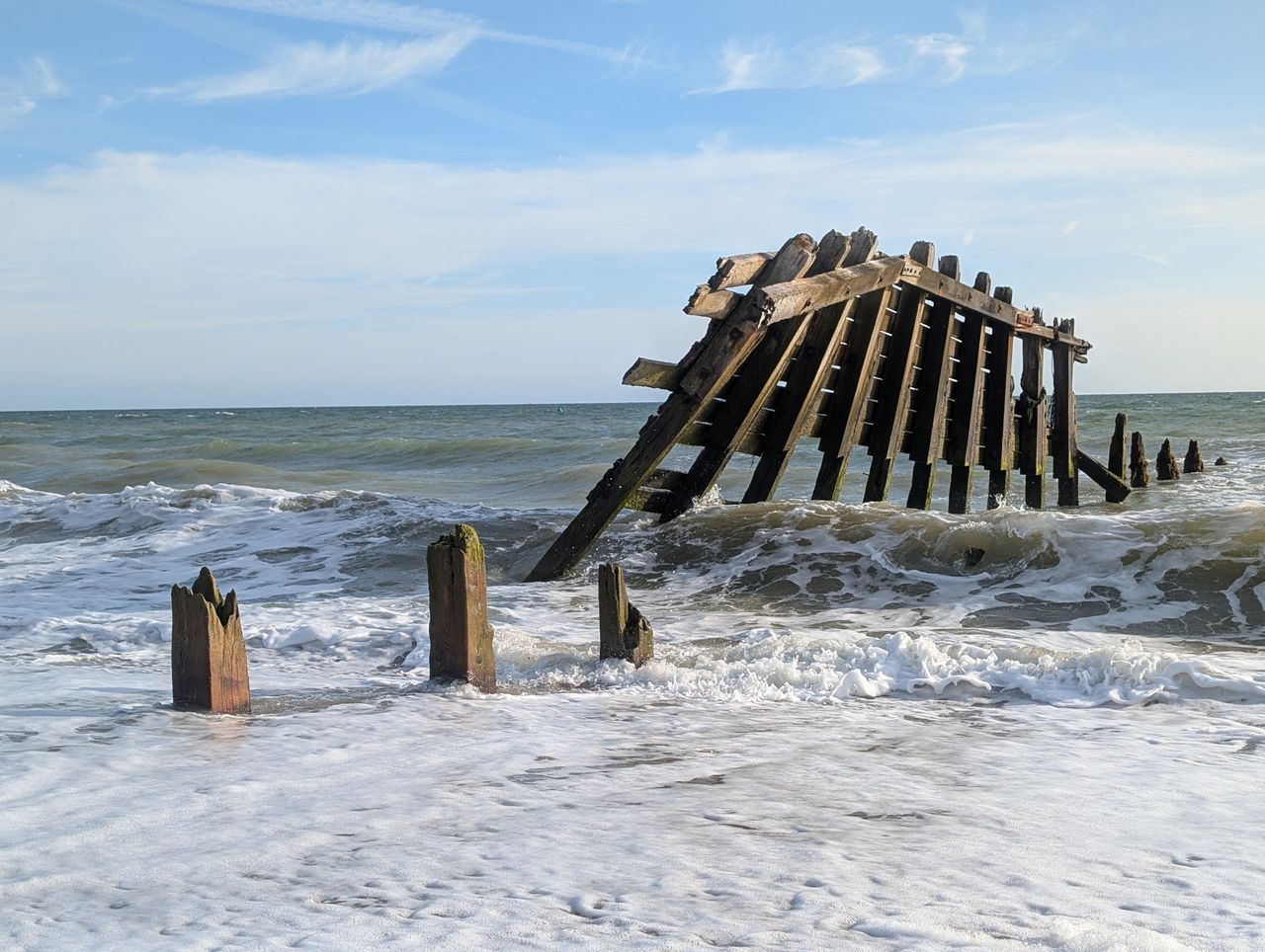 A damaged groyne on a UK beach, the high tide is smashing into it