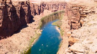 A bird's eye view of a blue river winding through a rocky valley. 