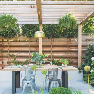 pergola with a dining table and chairs in the garden