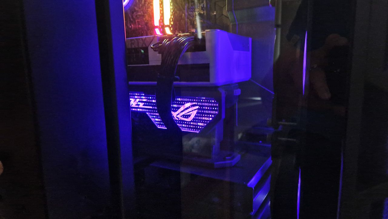 The Asus ROG Herculx GPU support bracket in a PC with its lights shining purple