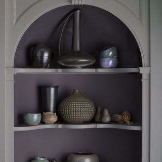 A close up shot of a built in shelf unit holding decorative vases and pots