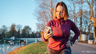 Woman looking at phone while stretching after a run