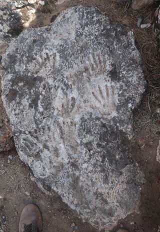 photograph shows hand and footprints preserved in limestone