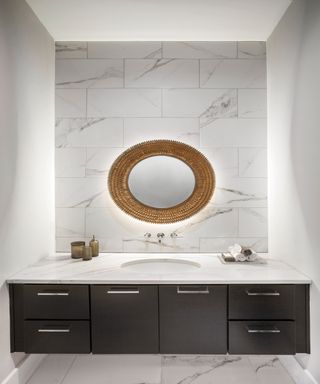 White bathroom with wooden accent vanity unit and round mirror with lighting