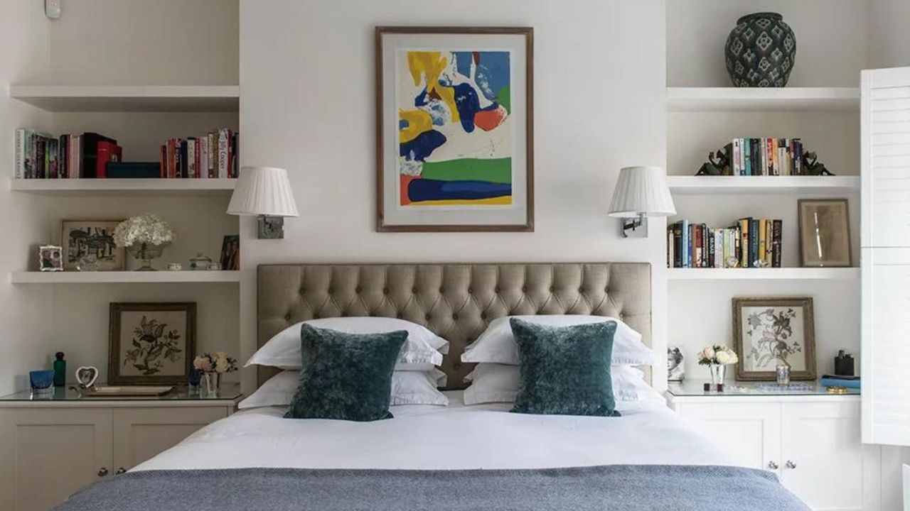 A bed flanked by open shelving, with blue scatter cushions