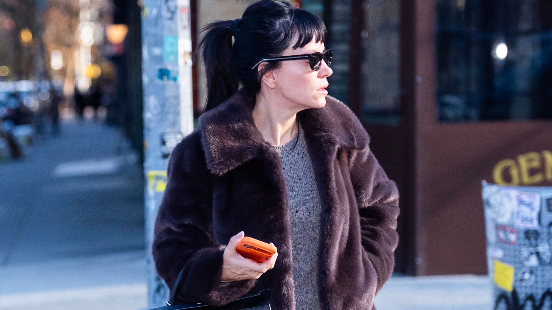 Lily Allen wears Hush fur jacket with a grey jumper a black leather skirt black lug-sole boots and a black Hermes bag and black sunglasses.