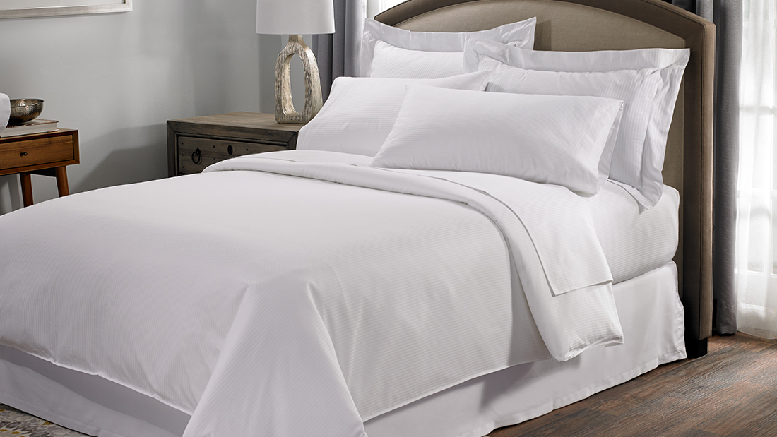 The Hilton mattress on a bed frame in a Hilton hotel room, dressed in Hilton bedding