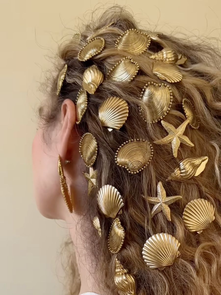 A woman with wavy hair wearing many Lelet NY clips in seashell and starfish shapes in her hair.