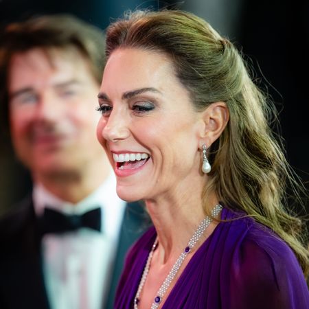 Princess Kate laughing in a purple gown with Tom Cruise standing behind her
