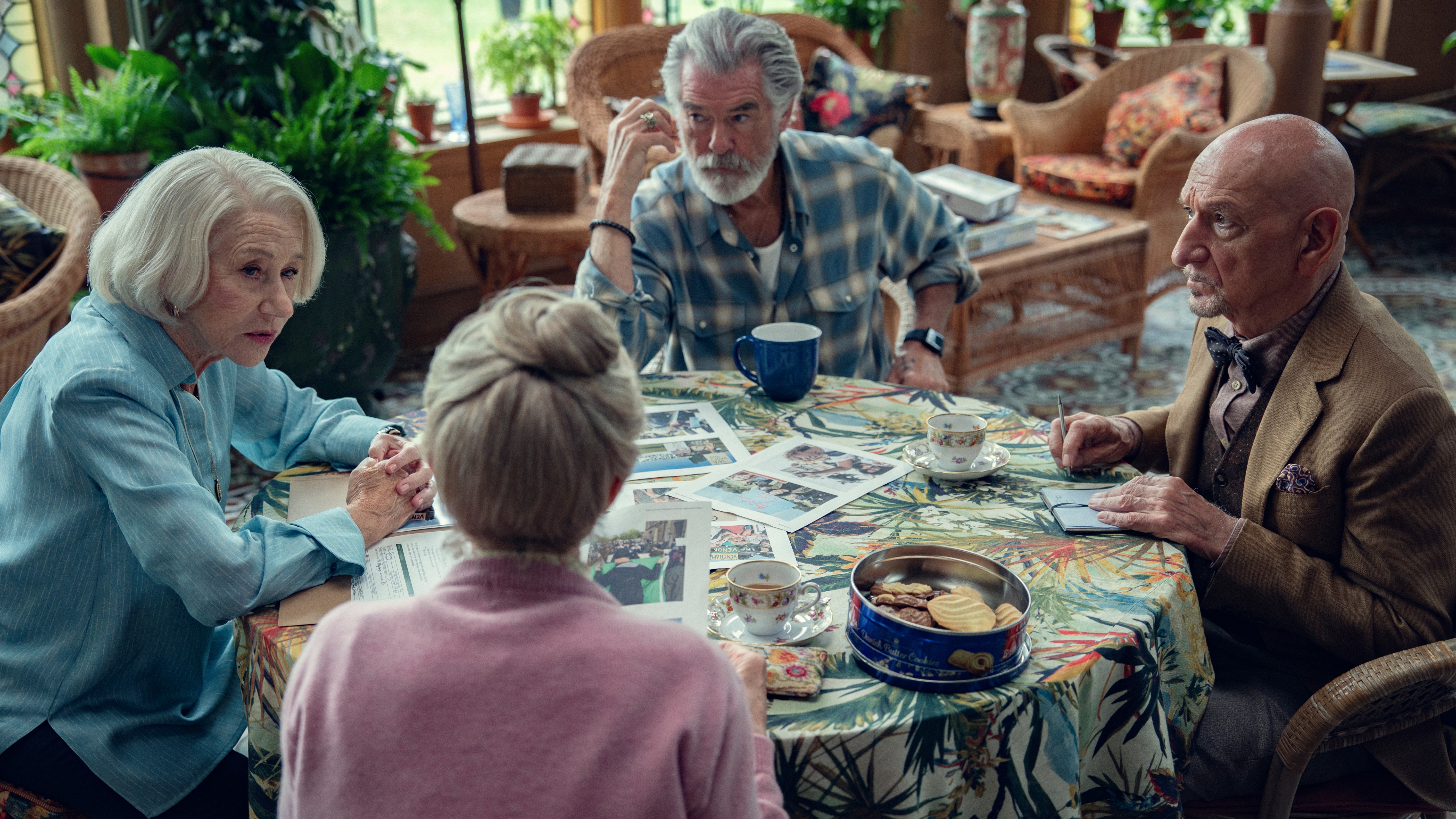 L-R: Helen Mirren, Celia Imrie, Pierce Brosnan and Ben Kinsley sit around a table in a scene from Netflix's "The Thursday Murder Club" movie