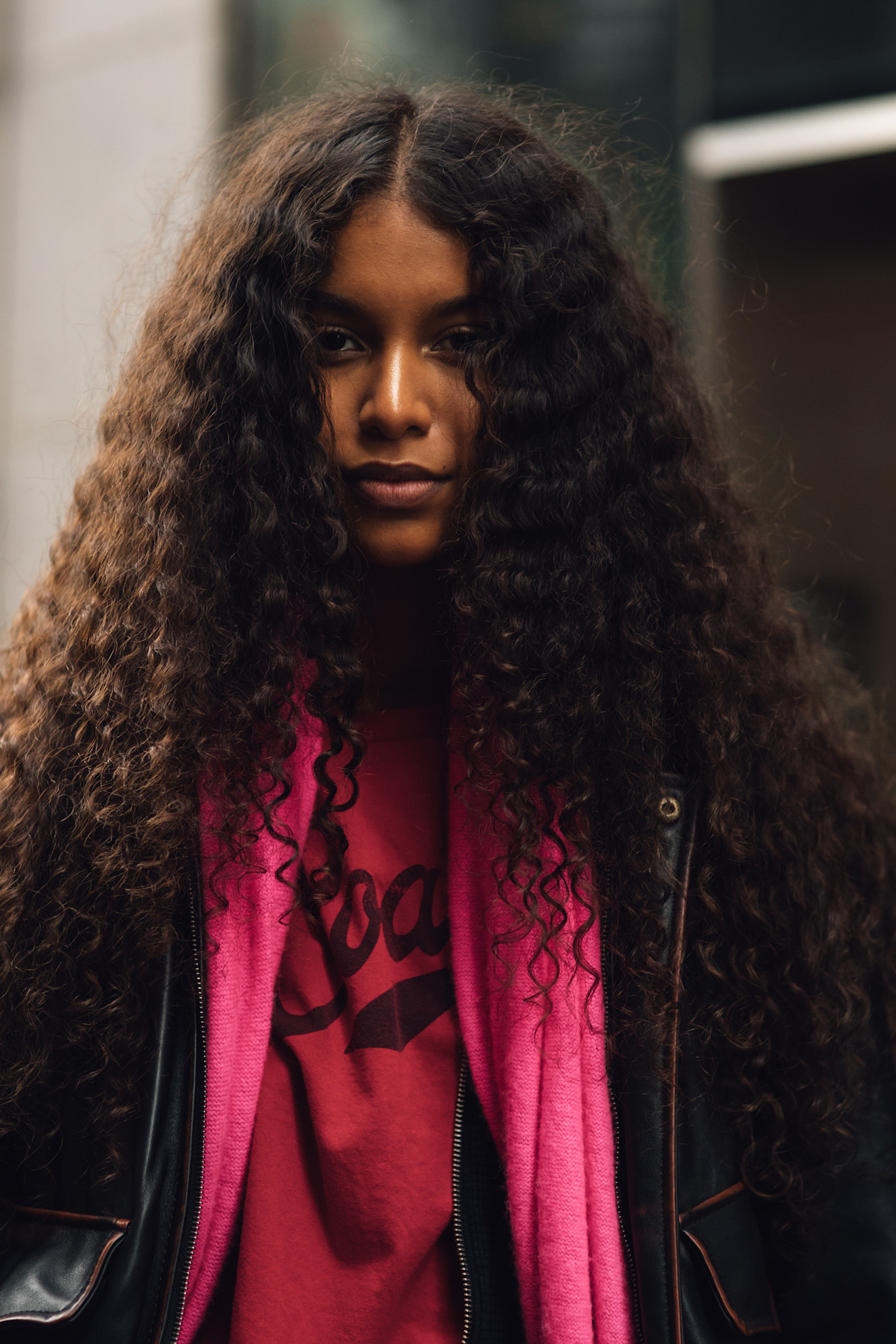 a woman with brunette curly hair and a pink scarf and t-shirt