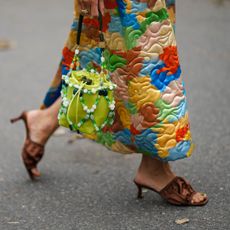 A guest a Copenhagen fashion week wears a multicoloured, quilted skirt, brown satin sandals and a brown pedicure colour