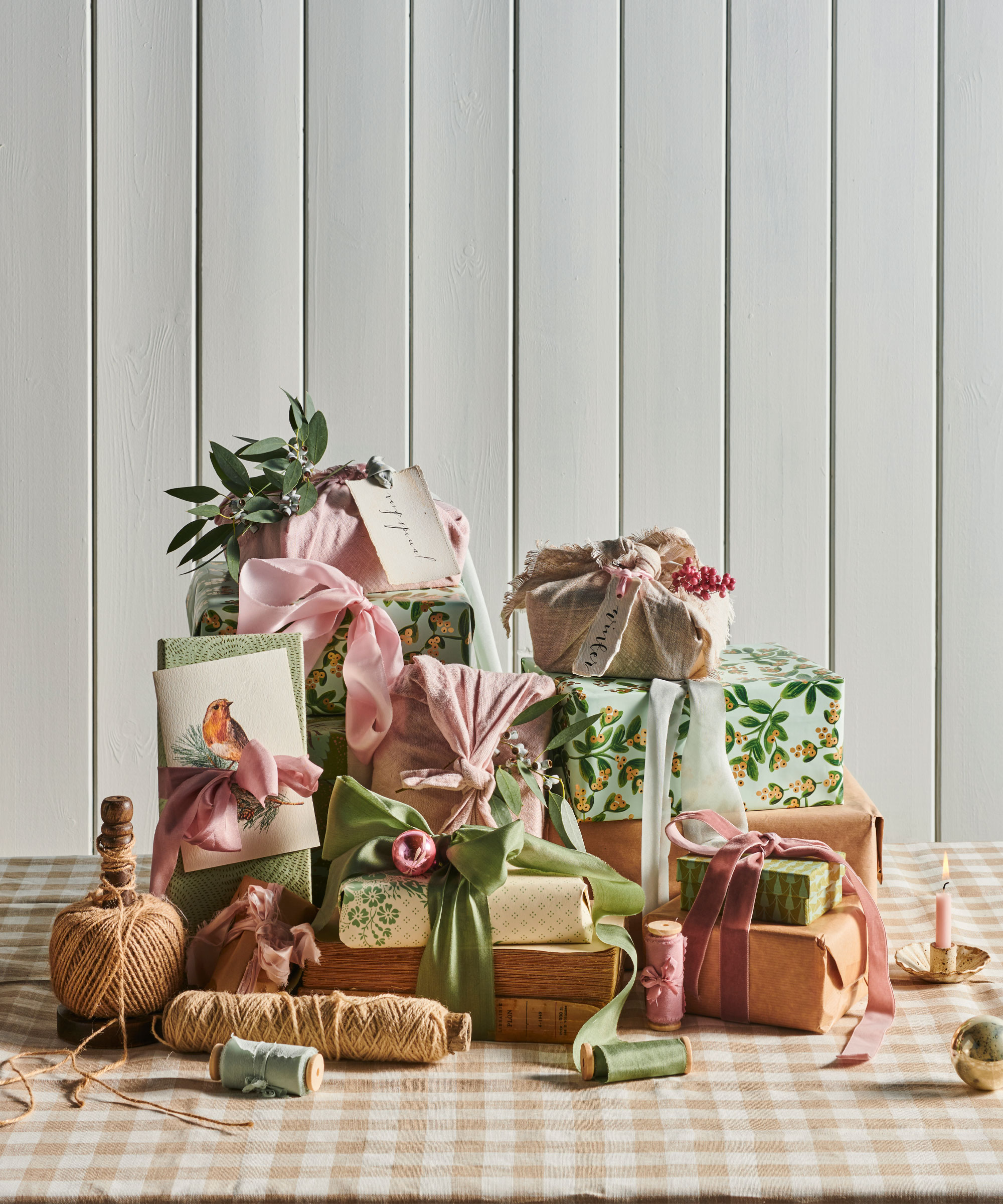 Wrapped christmas presents in brown and colorful pastel paper, decorated with ribbons and accessories, string, christmas foliage