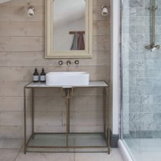 coastal bathroom with metal vanity unit and sink, bare wood on walls, vintage mirror, wall lights, stone floor, shower to right