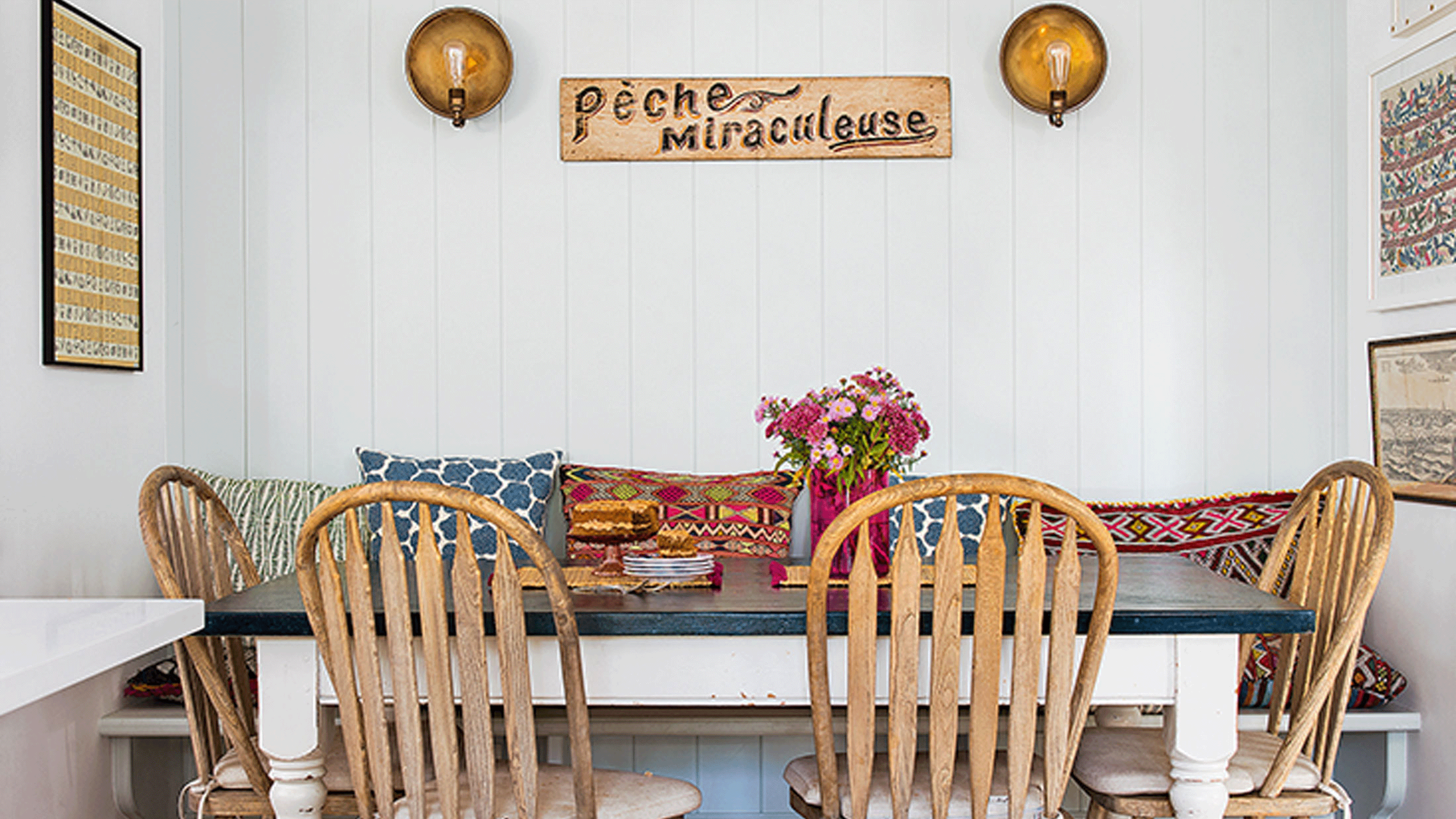 white kitchen area with dining table and hanging lights