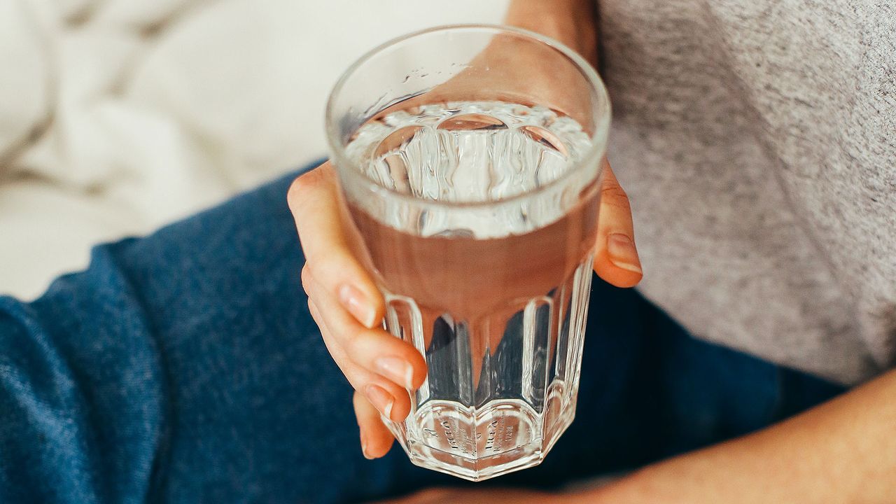 Person holding a glass of water in bed