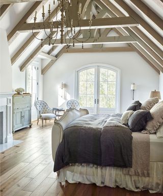 layered up bed with a romantic set of bed linens and a floating valance sheet, rustic beams overhead
