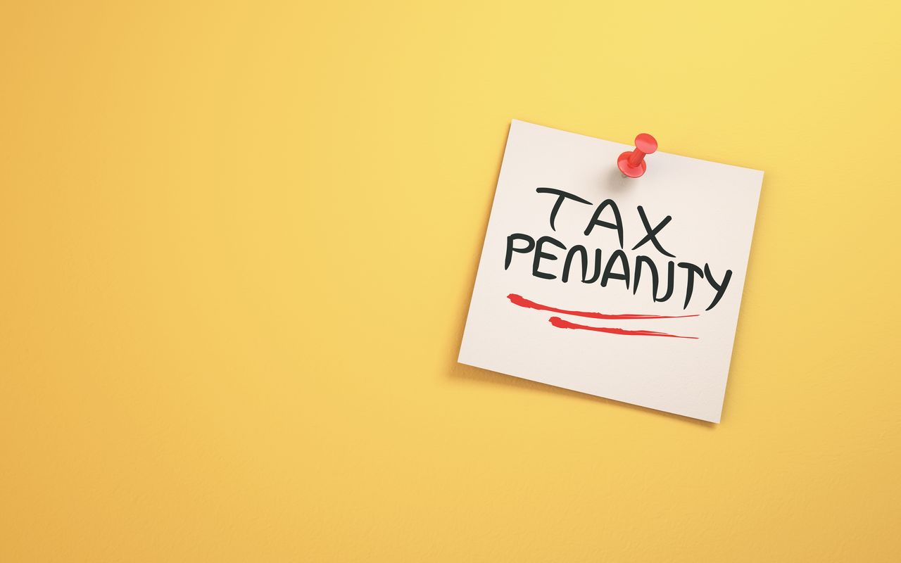 Tax Penalty Text Written on Note Paper Sitting on Yellow Background