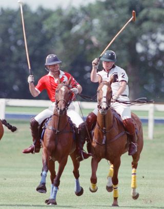 King Charles raising a mallet in the air while playing polo with James Hewitt in 1991