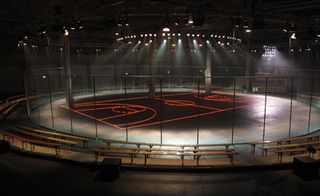 neon basketball court on the Halle Freyssinet's concrete floor with wooden benches arranged around a circular schoolyard fence