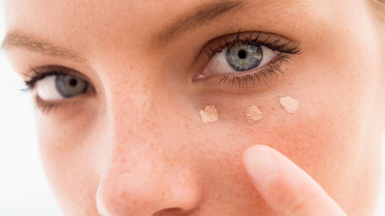 Woman with dots of concealer under her eyes