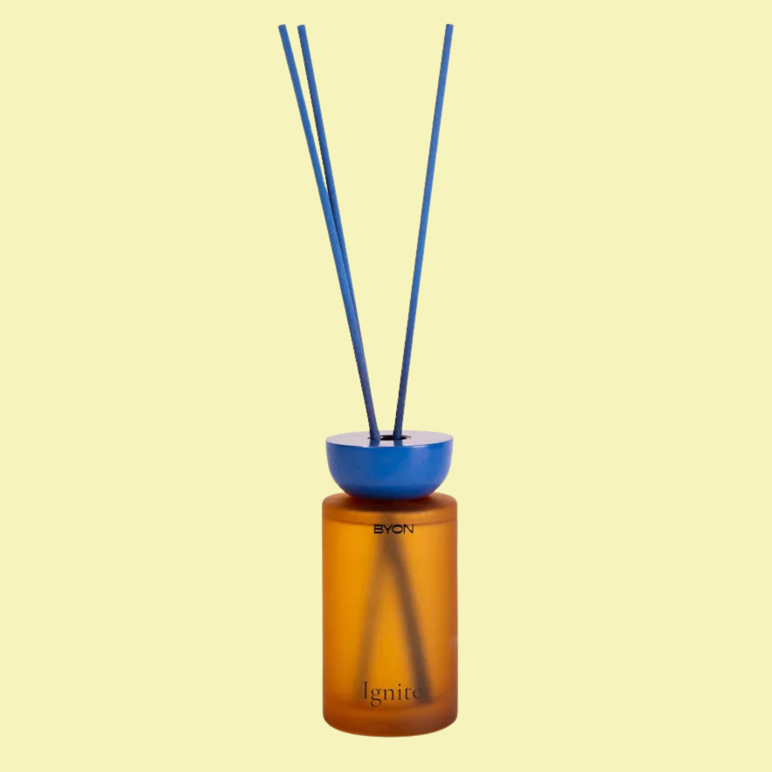 A blue and orange reed diffuser against a light yellow backdrop