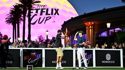 Golfer Tony Finau and F1 driver Pierre Gasly high-five in front of the Las Vegas Sphere - which is lit up with the Netflix Cup logo