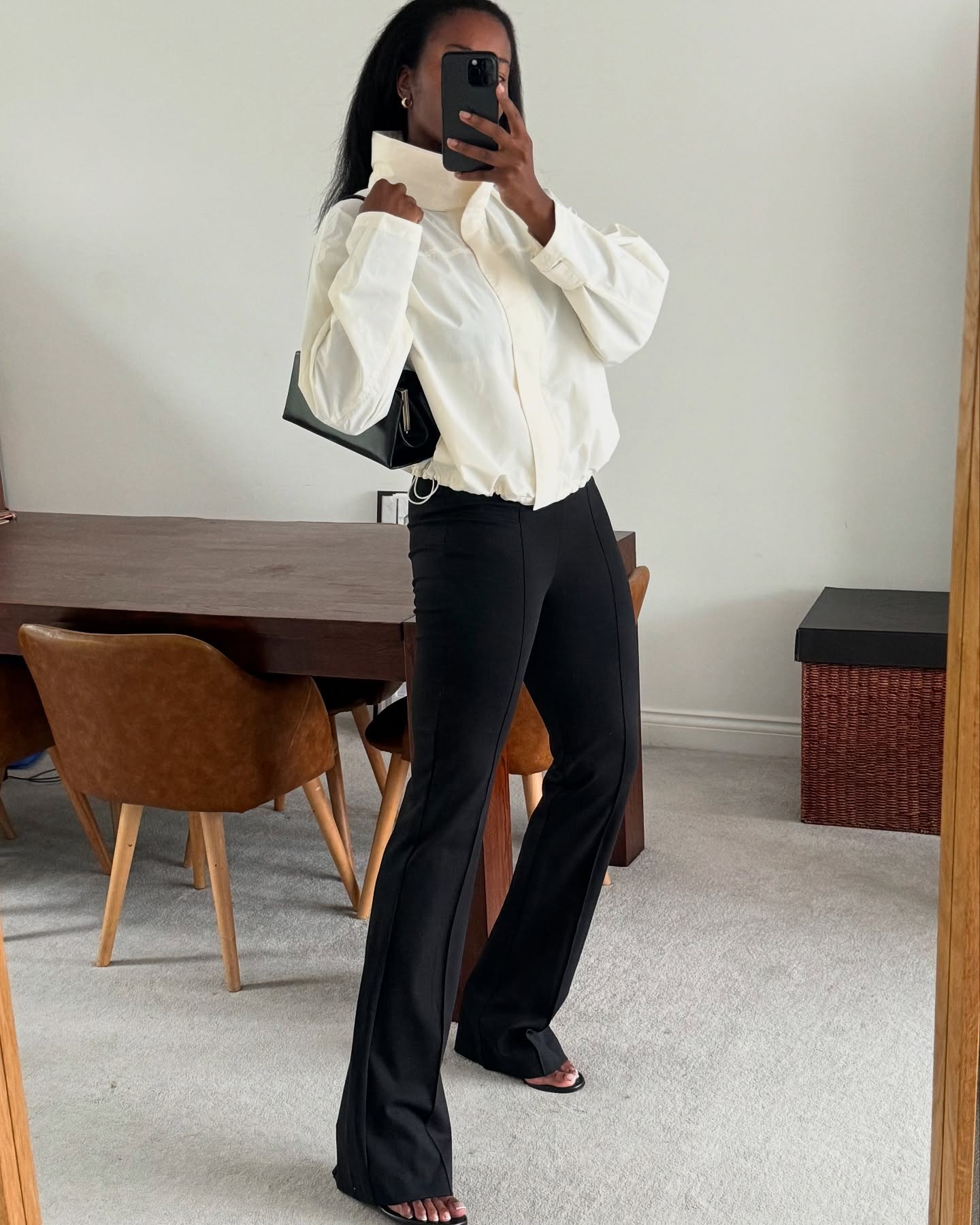 @nlmarilyn wearing a sporty ivory-colored jacket with black trousers and open-toed heels.