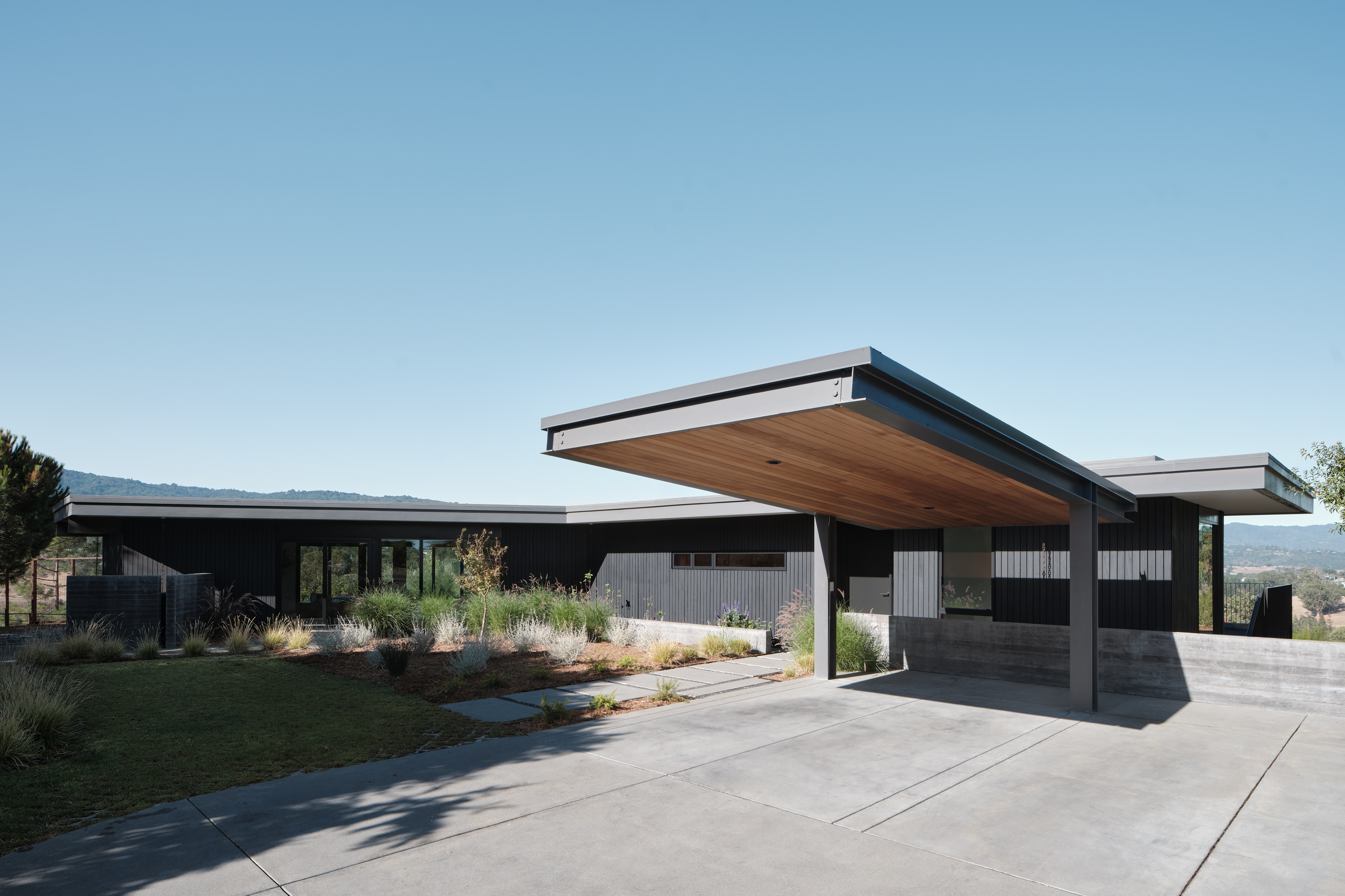 Hilltop Residence by Michael Hennessey Architecture, a modernist inspired home, low lying and linear with timber ceilings and black accents