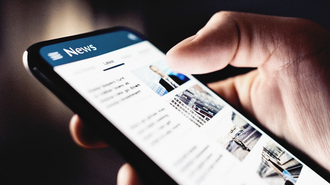 Close-up of a hand looking at news on a smartphone