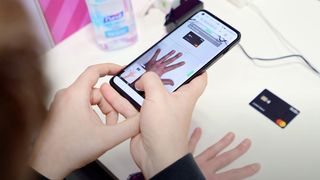 A demo of the Circular Ring 2's digital sizing feature with a user pointing a smartphone camera at their hand next to a credit card-sized piece of plastic