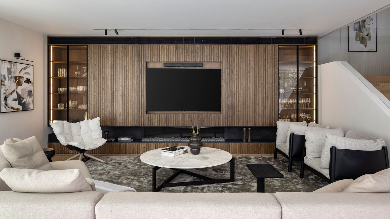 A living room space with a sofa cream colored sofa and accent chair. A TV also sits in the middle of the space