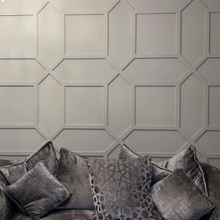 Grey wall with geometric panel design and sofa and cushions