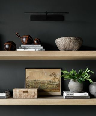 Two wooden shelves filled with art and decorative objects against a dark gray wall