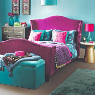 Grey carpet with blue rug and blue ottoman, fuscio bed and blue and pink bedding