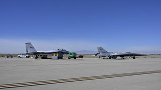 two sleek, small jets sit on a concrete tarmac in the desert