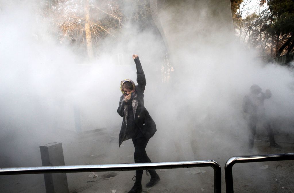 An Iranian woman raises her fist amid the smoke of tear gas at the University of Tehran during a protest driven by anger over economic problems, in the capital Tehran on December 30, 2017.