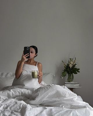 Content creator Mobina Peiman wearing a sheet mask and holding a mug