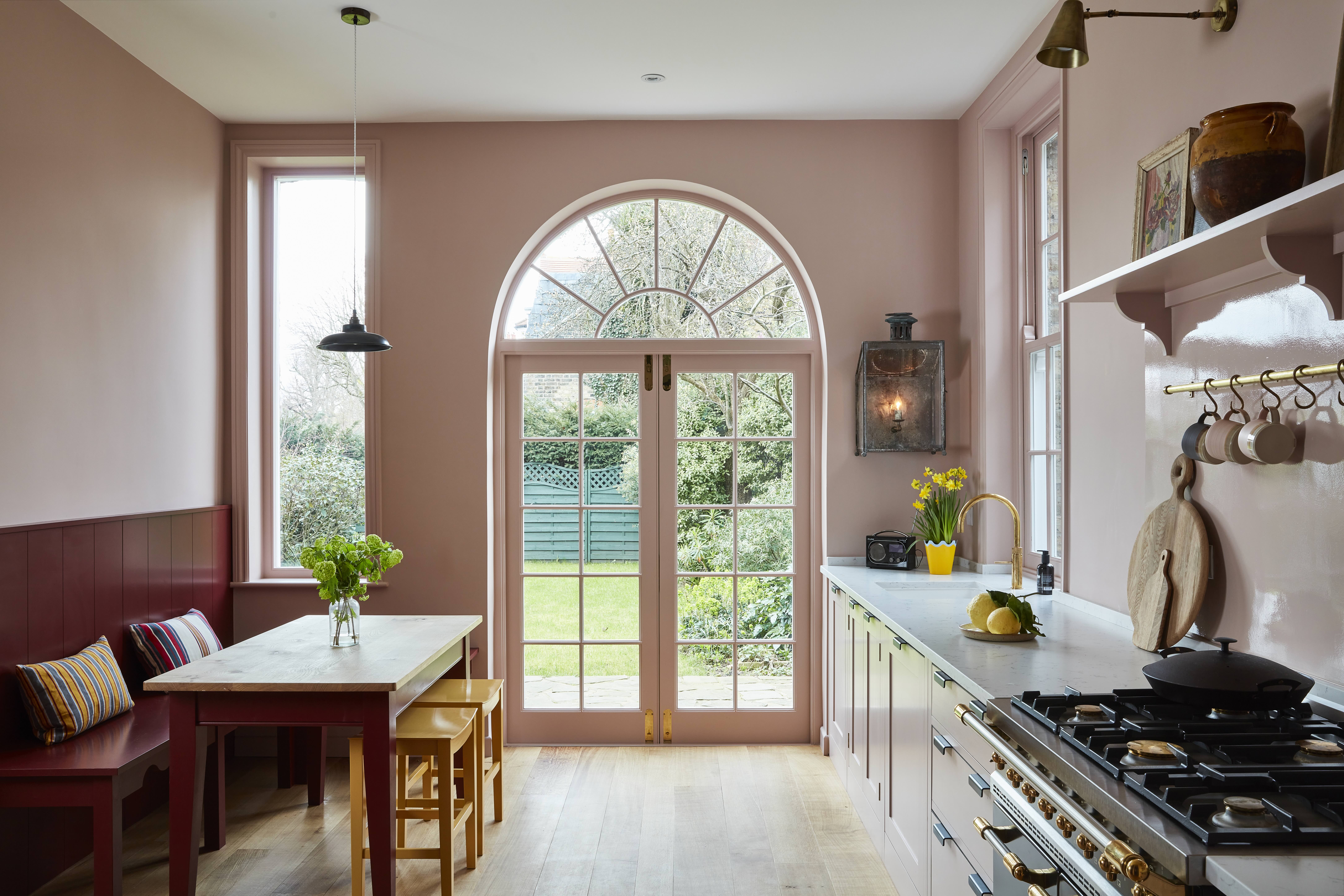 A contemporary kitchen in a soft contrast palette of pink, red, wood, marble, and metal colors and materials