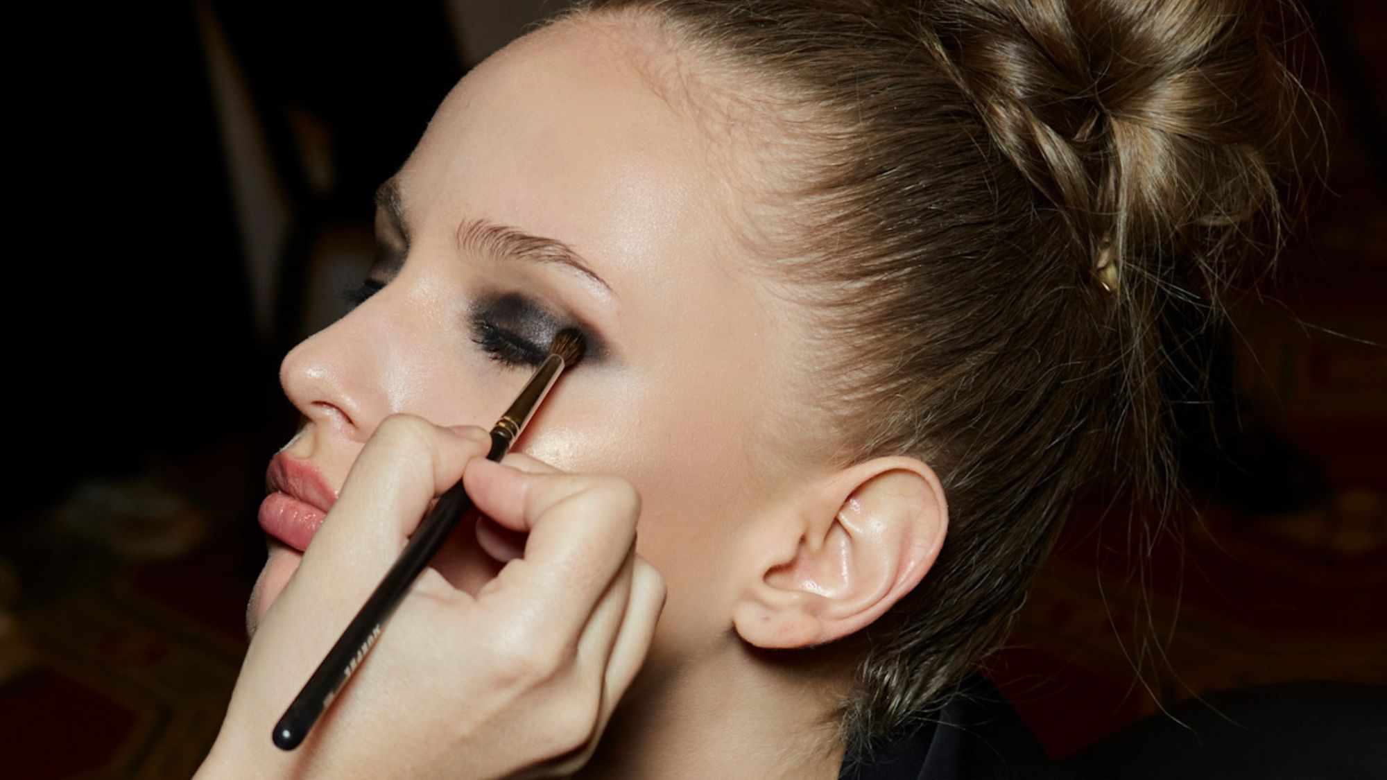 blonde model backstage having smokey eye makeup applied