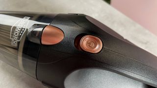 A close-up of the rose gold power button and dust cup release.