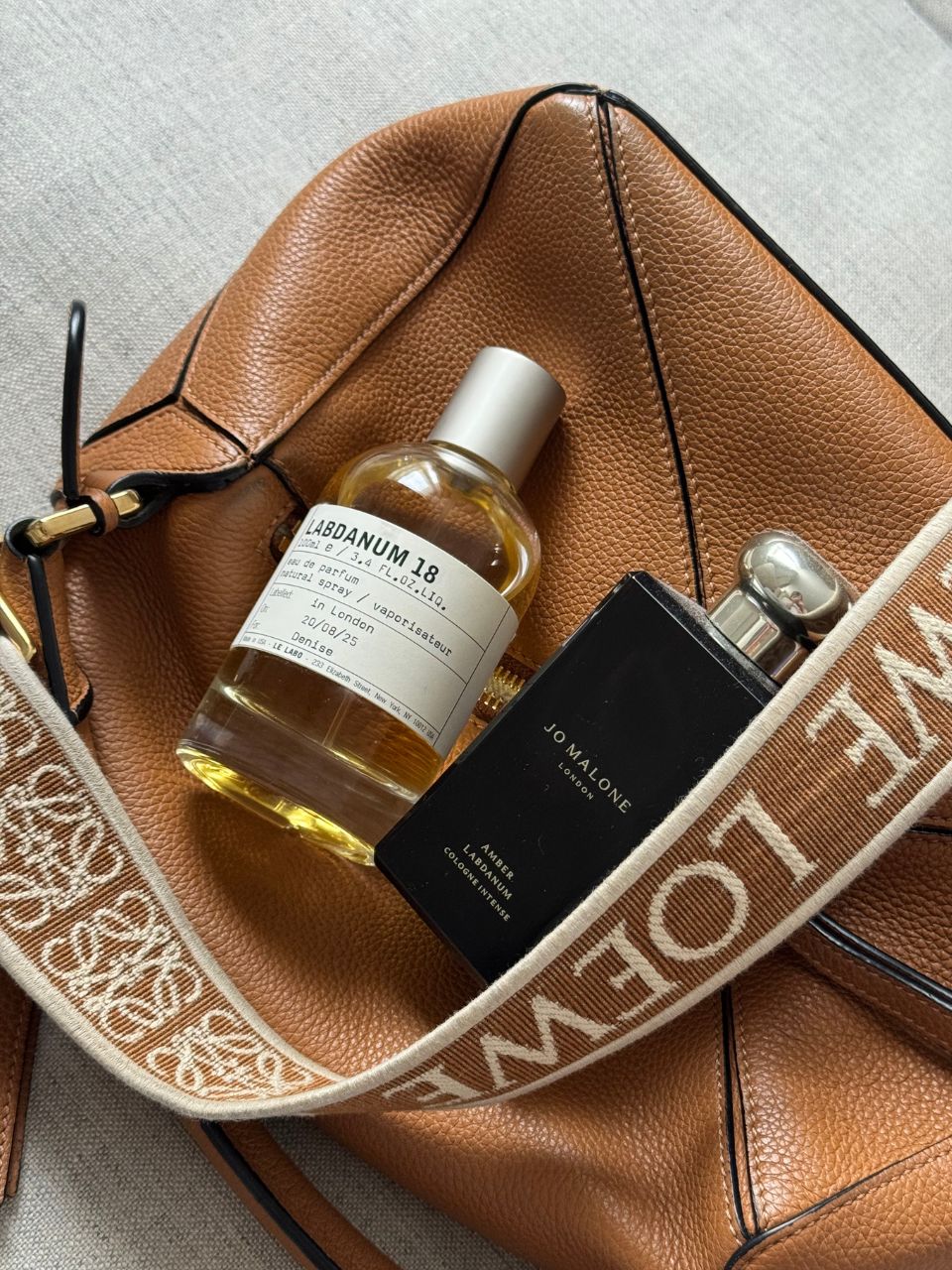 Uma imagem de dois perfumes labdanum exibidos em cima de uma bolsa de couro