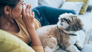 Woman with allergies sitting on couch with her dog