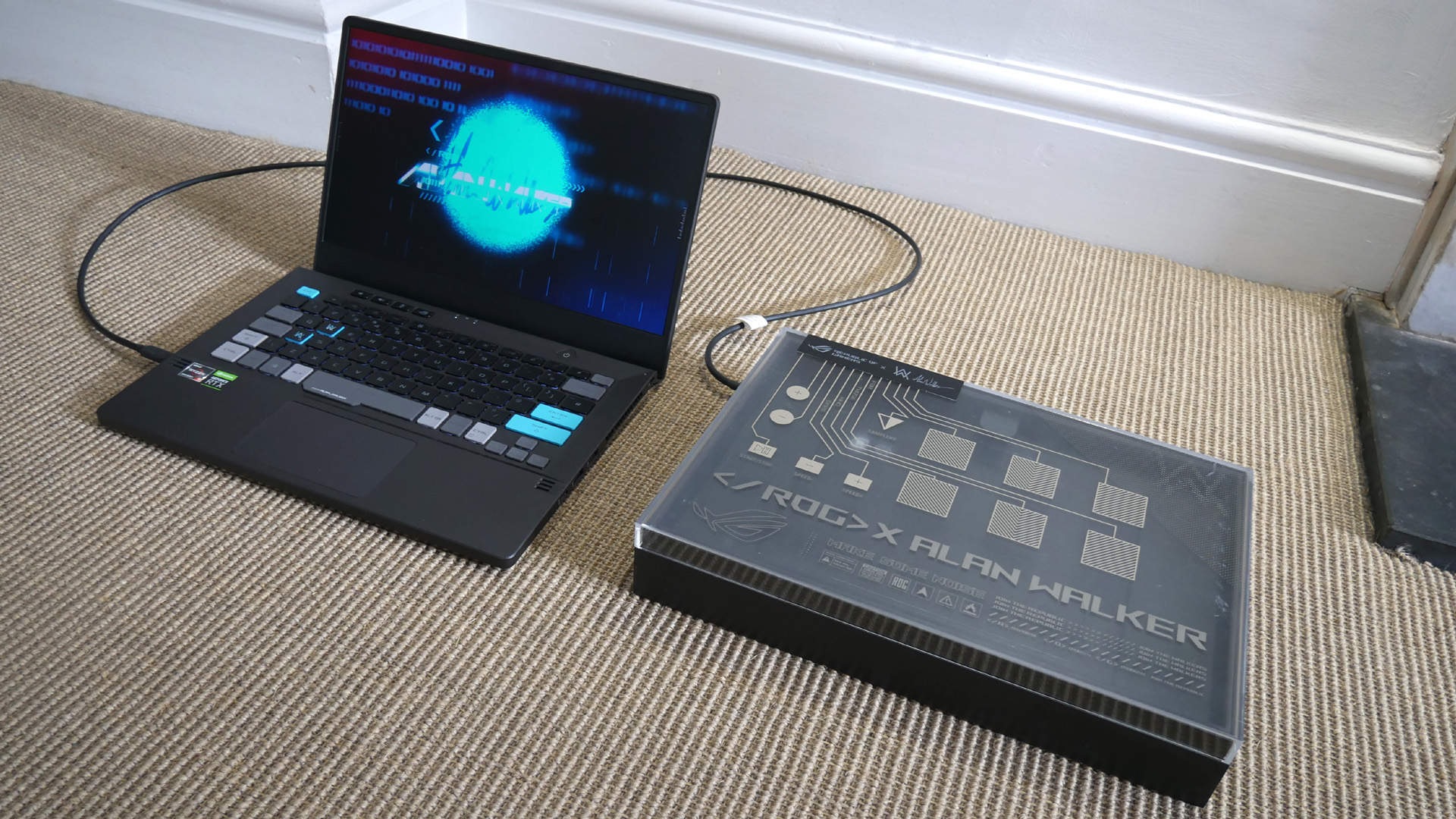 Asus ROG Zephyrus G14 Alan Walker Special Edition with its synth or mixing pad box on a carpeted floor