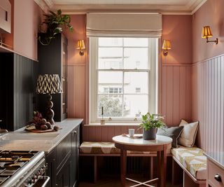 small kitchen diner with pink colour scheme and built in seating area around small round table