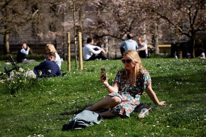 Woman enjoying sunshine in park as fines for breaking lockdown rules increase