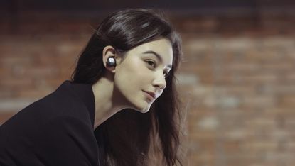 Astell&Kern AK UW100 true wireless earbuds being worn by a woman with black hair