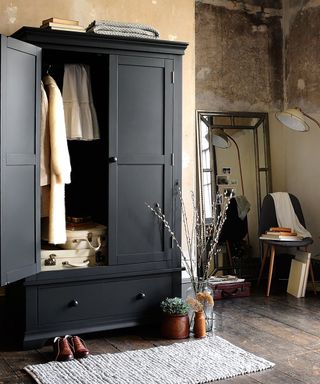 A black wardrobe by the Cotswold Co with distressed wall decor
