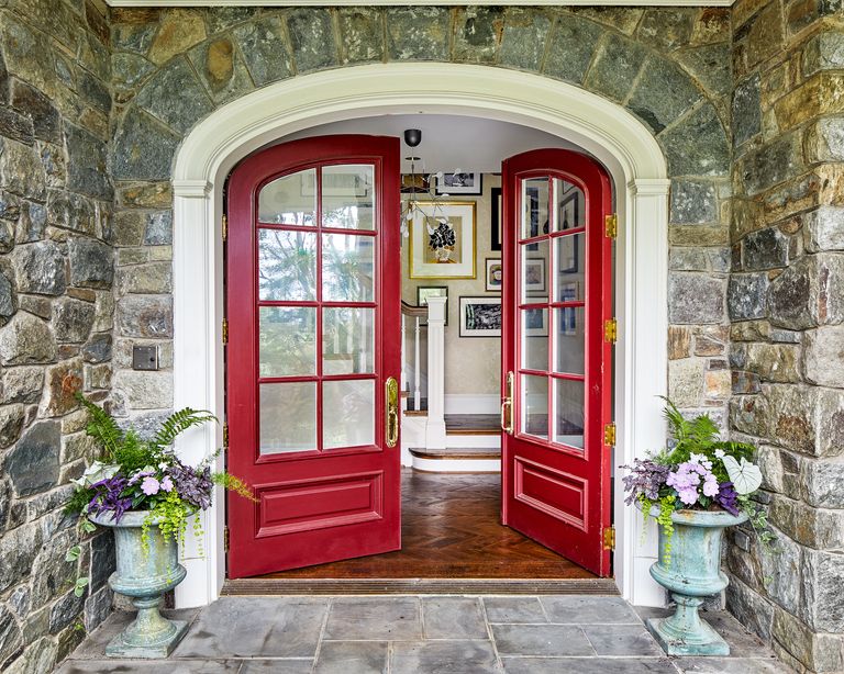 An arched front double front door, painted red with glass windows